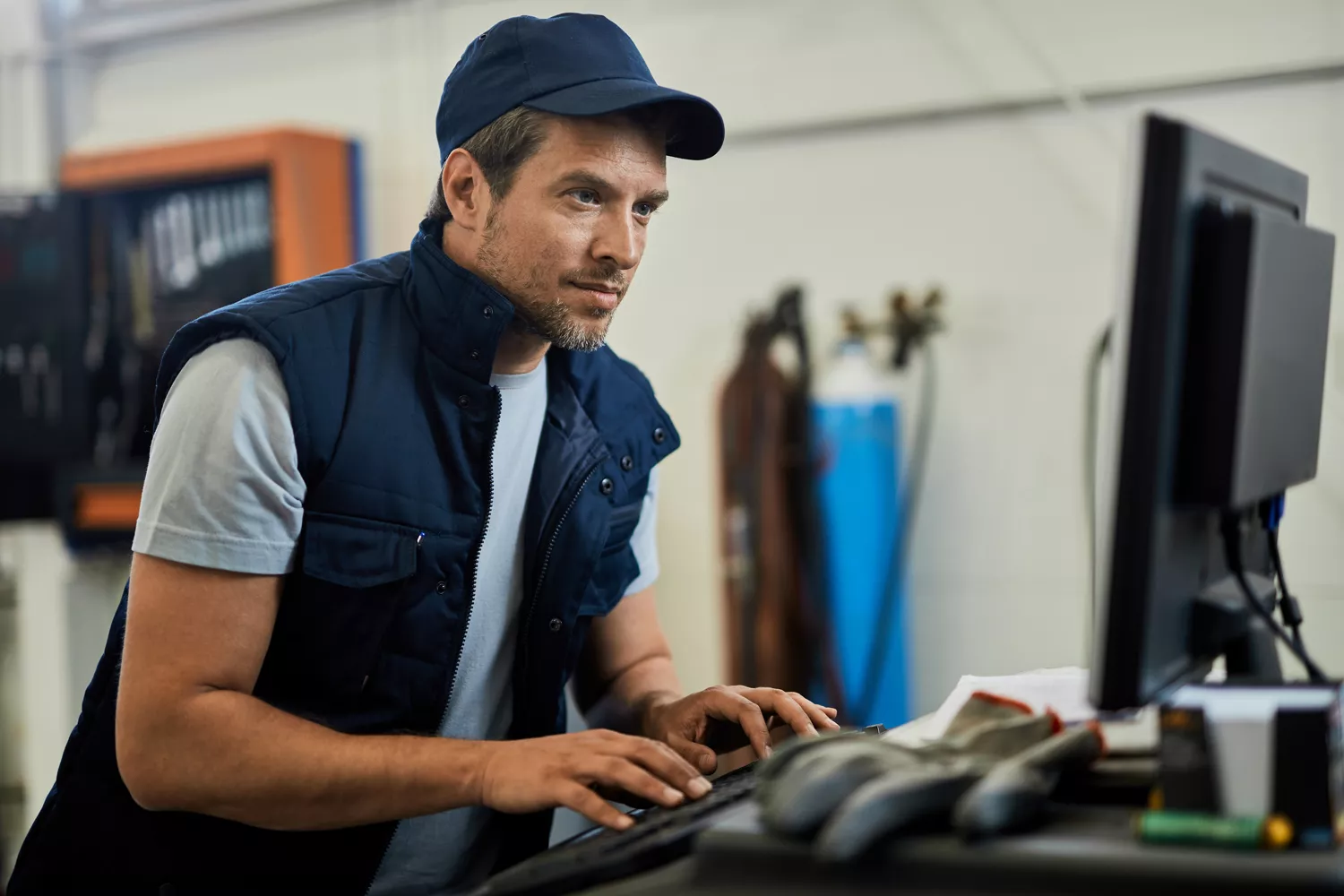 Service employee with blue cap sitting at a computer